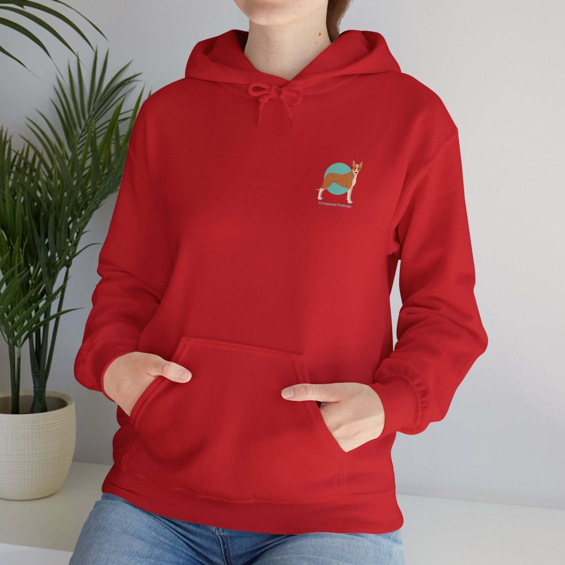 Unisex red hoodie featuring a small embroidered Portuguese Podengo design, perfect for dog lovers, shown worn by a woman in a casual setting.