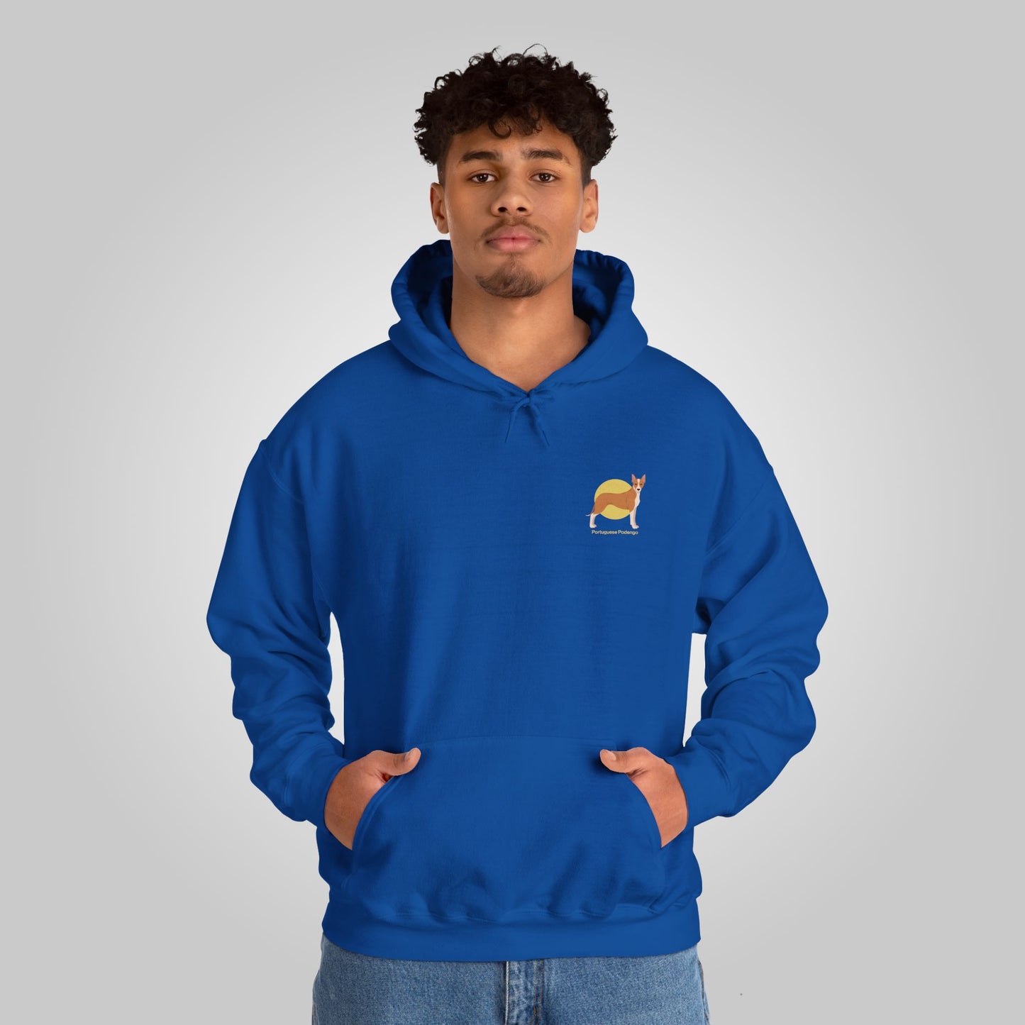 Young man wearing a blue Portuguese Podengo dog hoodie, hands in pockets, looking at camera