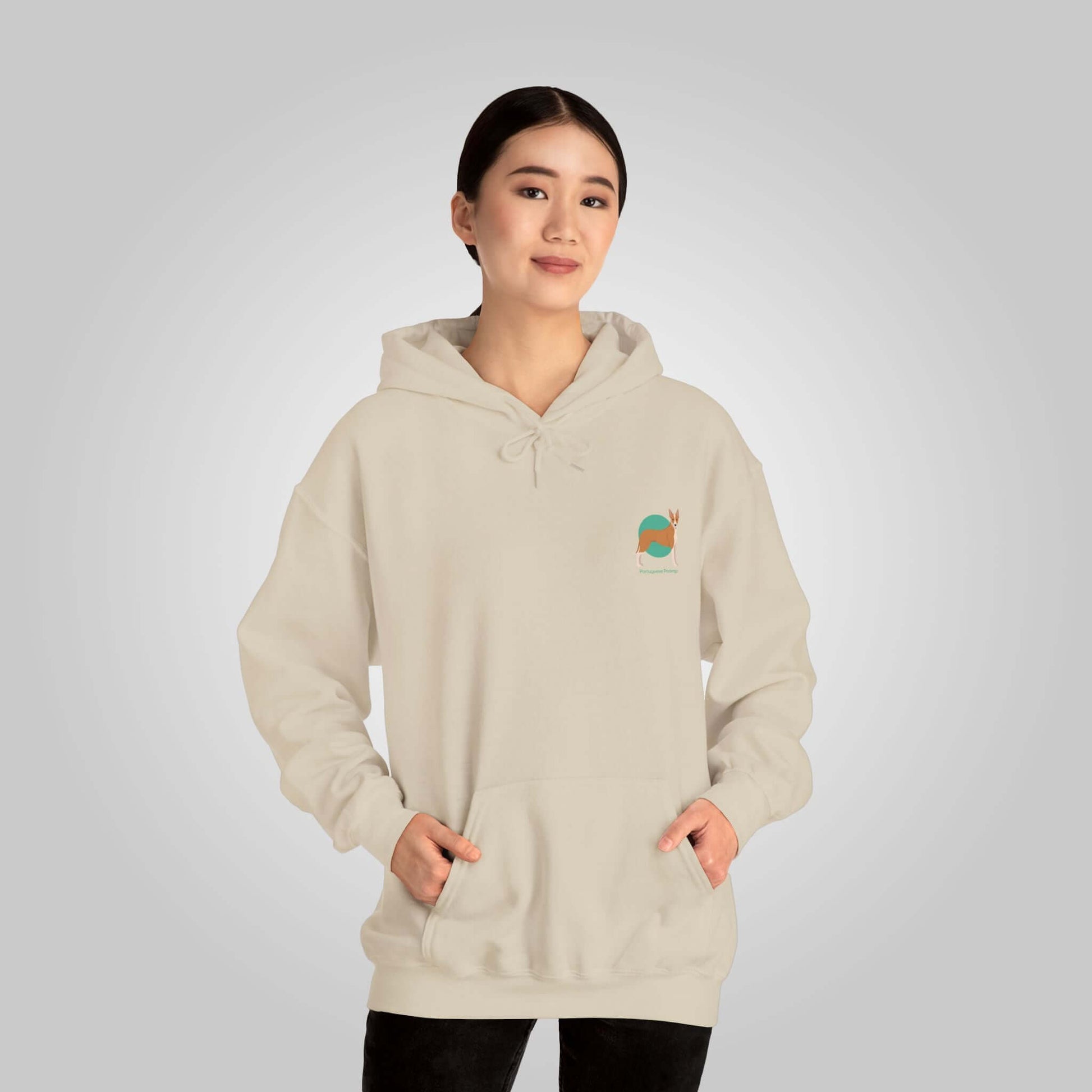 Woman wearing a beige Portuguese Podengo dog hoodie, hands in pockets, on a neutral background